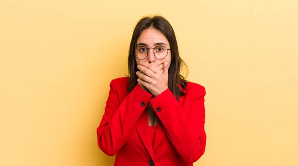 young hispanic woman covering mouth with hands with a shocked. business concept - Foto, Bild