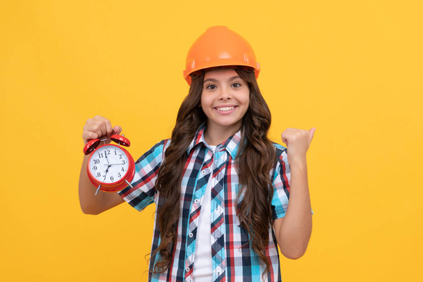 successful workers day. future career. happy teen girl hold alarm clock. child in helmet - Photo, Image