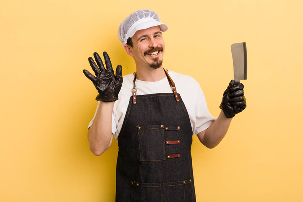 man smiling happily, waving hand, welcoming and greeting you. butcher concept - 写真・画像