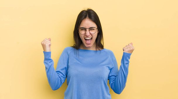 young hispanic woman shouting aggressively with an angry expression or with fists clenched celebrating success - Фото, зображення
