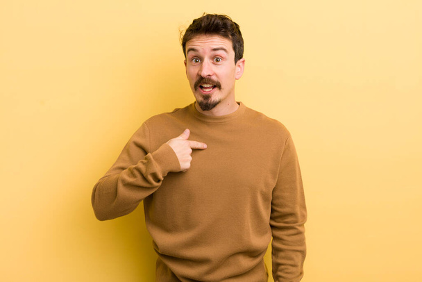 young hispanic man looking happy, proud and surprised, cheerfully pointing to self, feeling confident and lofty - Foto, Bild
