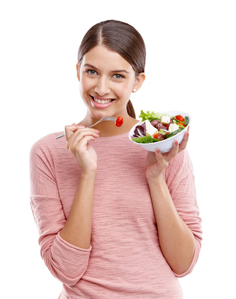新鮮でおいしい。健康的なサラダを食べる美しい若い女性のスタジオの肖像画. - 写真・画像