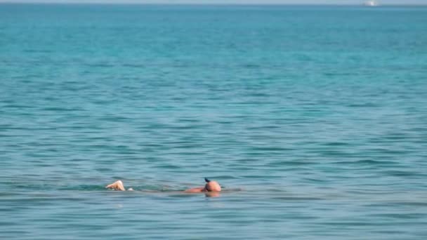 Nierozpoznawalny mężczyzna pływający z maską do nurkowania pod powierzchnią wody morskiej - Materiał filmowy, wideo