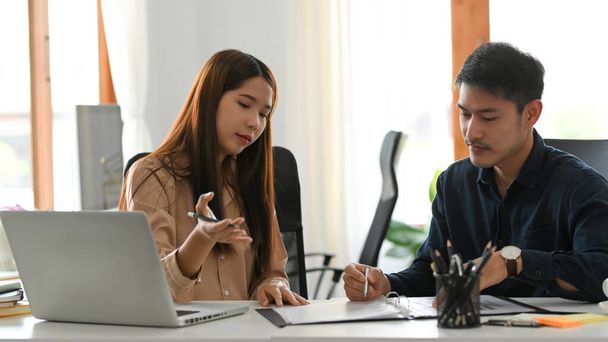 Азійська жінка-бізнесмен пояснює бізнес-стратегію своєму колезі в офісі. - Фото, зображення