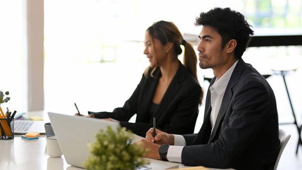 Un inteligente empresario asiático se concentra mientras escucha la presentación en la reunión. Empresarios en la reunión o reunión de la conferencia - Foto, imagen