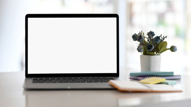 オフィステーブルのラップトップコンピュータの白い画面のモックアップとオフィスアクセサリーを開きます。クローズアップ画像 - 写真・画像