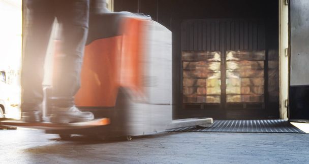 Motion Blur of Workers Driving Electric Forklift to Unloading Packaging Boxes Inside Container. Přepravní nákladní distribuční sklad - Fotografie, Obrázek