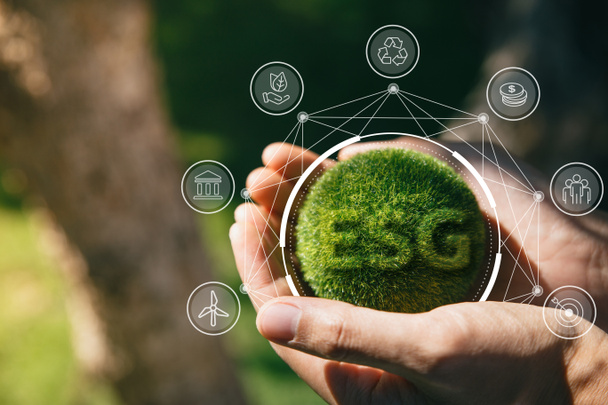 A zöld földet tartó ember keze ESG ikon a környezetvédelemért Társadalom és kormányzás, a világ fenntartható környezetvédelmi koncepciója. - Fotó, kép
