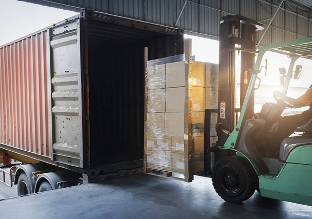 Vorkheftruck Tractor Pakketdozen laden in Cargo Container bij Dock Warehouse. Bezorging. Scheepvaart Pakhuis Logistiek. Vrachtzending. Goederenvervoer per vrachtwagen. - Foto, afbeelding
