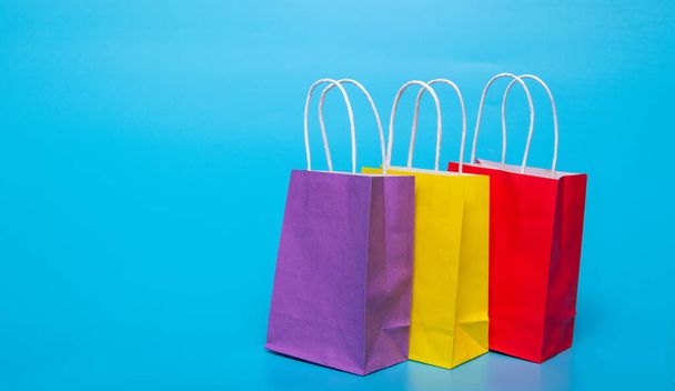 three colored paper bags on a blue background - Foto, Imagem