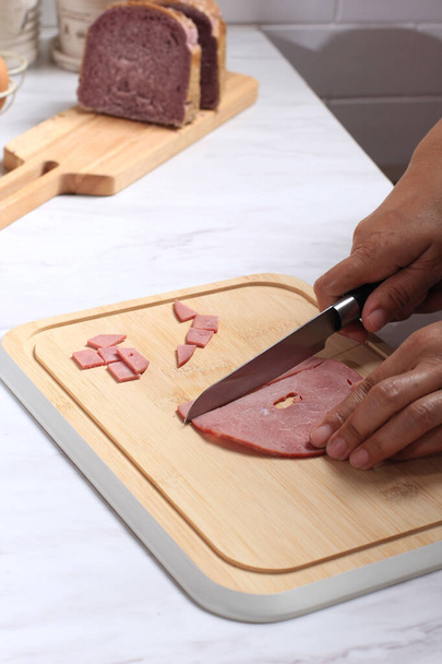 Asian Chef fêmea mão cortada carne fumada em pedaços pequenos. Processo de cozinha na cozinha, Fazendo café da manhã do pão - Foto, Imagem