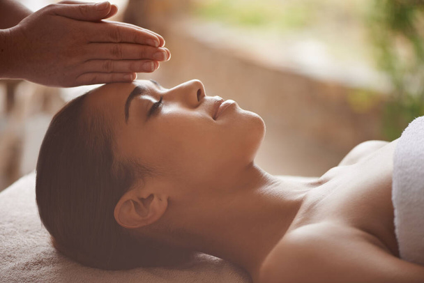 Masajeando el cuerpo y la mente. Foto de una hermosa joven recibiendo un masaje en la cabeza en un spa. - Foto, Imagen