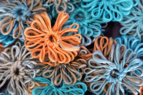Niedliche handgestrickte Wollblumen in blau, grün und orange - Foto, Bild