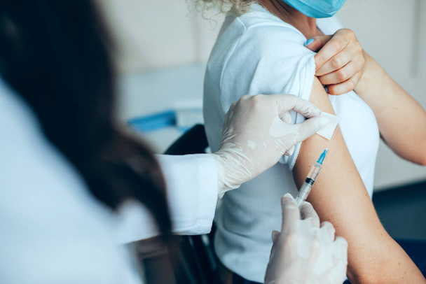 Female doctors hands making shot in shoulder of a patient, immunization while pandemic situation. Closeup for lifestyle design. Coronavirus vaccination - Foto, Imagem