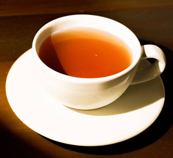 A cup of iced tea is set on a dark wooden floor. Breakfast. - Foto, Imagen