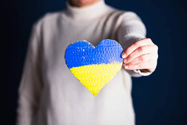 Heart shaped flag of Ukraine in female hands. The concept of solidarity with the citizens of Ukraine. - 写真・画像