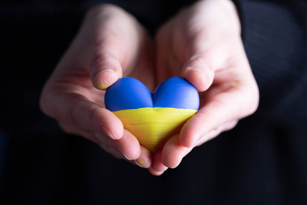 Heart shaped flag of Ukraine in female hands. The concept of solidarity with the citizens of Ukraine. - Valokuva, kuva