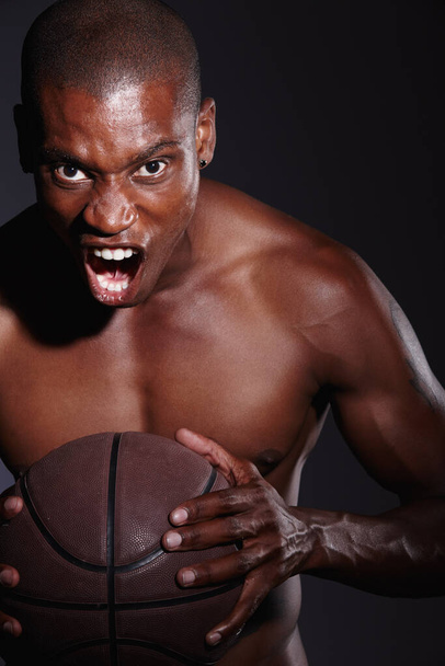 Kihívlak. Stúdió portré egy eltökélt fiatal kosárlabda játékos álló ellen fekete háttér. - Fotó, kép