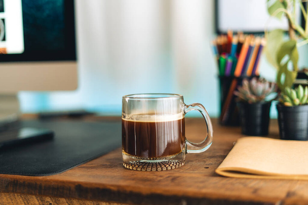 Black coffee in a mug on the desk in the house - Фото, зображення