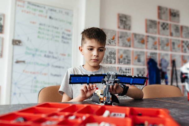 A boy and a robot assembled from a designer with a bow on his chest. A gift and a friend. School of Robotics. STEM education. - Fotó, kép
