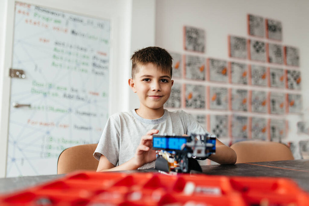 A boy and a robot assembled from a designer with a bow on his chest. A gift and a friend. School of Robotics. STEM education. - Foto, afbeelding