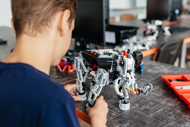 Kind spielt mit einem Roboterspielzeug, das vom Designer zusammengebaut wurde - Foto, Bild