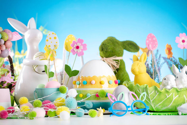 Easter decorations. Easter bunny, easter eggs in basket and cabbage leaf. Blue background. - Photo, Image