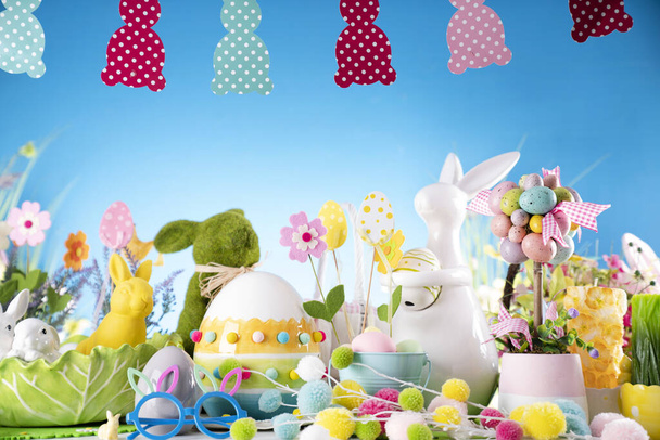 Easter decorations. Easter bunny, easter eggs in basket and cabbage leaf. Blue background. - Фото, изображение