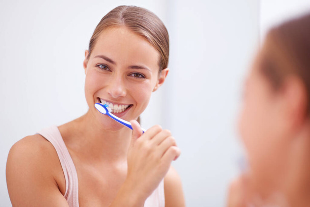 A cuidar do sorriso dela. Uma jovem mulher escovando os dentes. - Foto, Imagem