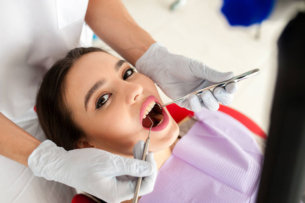 Beautiful girl treats teeth in dentistry. - Foto, Imagen