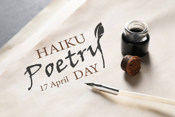 Folha de papel com texto HAIKU POETRY DAY 17 ABRIL e pena caneta com tinta na mesa, close-up - Foto, Imagem