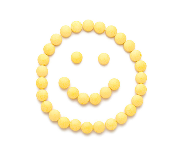 Χαρούμενο χαμόγελο από κίτρινα χάπια σε λευκό φόντο - Φωτογραφία, εικόνα