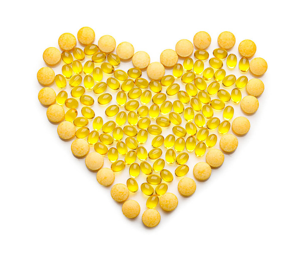 Herzform aus gelben Pillen auf weißem Hintergrund - Foto, Bild