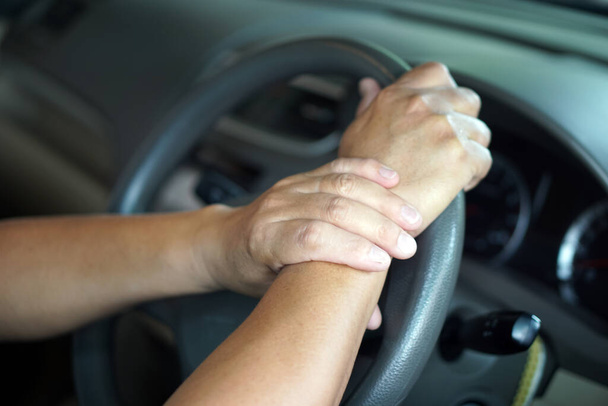 Concept : Painful, injury from driving. Driver's hand holds his wrist on steering wheel.     - Photo, Image