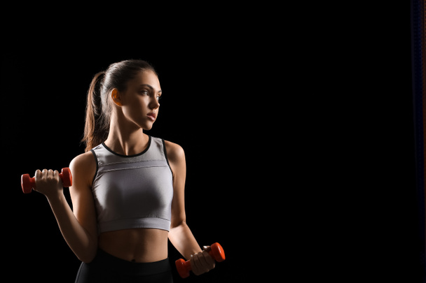 sportliche junge Frau mit Hantel auf schwarzem Hintergrund - Foto, Bild