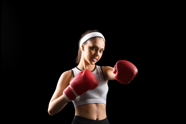 Sporty teenage girl with boxing gloves on black background - Photo, Image