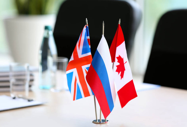 Brytyjskie, rosyjskie i kanadyjskie flagi na stole urzędującym - Zdjęcie, obraz