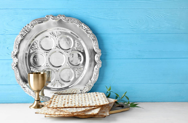 Pascha Seder bord met kopje wijn en matza op tafel tegen kleur houten achtergrond - Foto, afbeelding