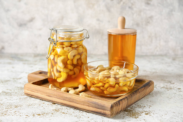 Board with sweet cashew nuts in honey on grunge background - Foto, Bild