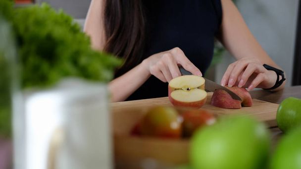Cropped shot healthy woman cutting fruits on a wooden board while making healthy vegan food in kitchen. - Φωτογραφία, εικόνα