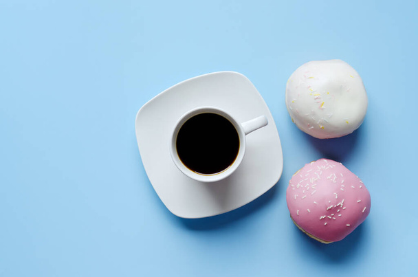 Morgen mit einer Tasse heißen Kaffees und süßen Donuts auf blauem Hintergrund. Tulpenstrauß. Draufsicht, Kopierraum, Attrappe. Flach lag er. Essen und Trinken. Frühjahrsferien.  - Foto, Bild