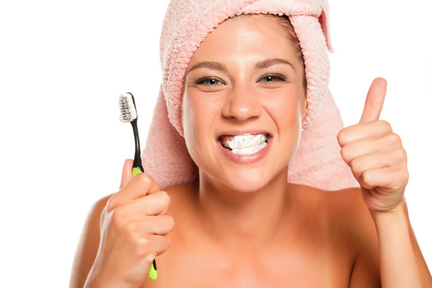 jeune femme posant avec brosse à dents et montrant pouces vers le haut fond blanc - Photo, image