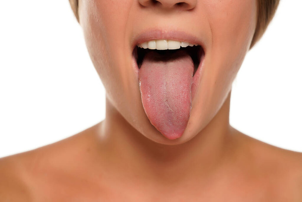 fiatal nő kinyújtja a nyelvét fehér háttér - Fotó, kép
