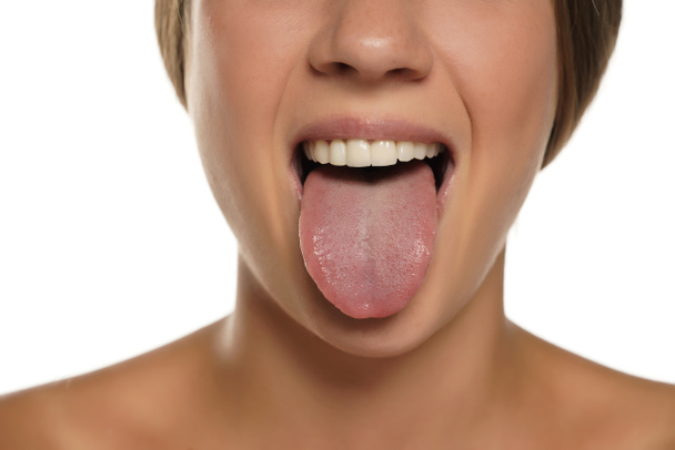 junge Frau streckt ihre Zunge auf weißem Hintergrund aus - Foto, Bild