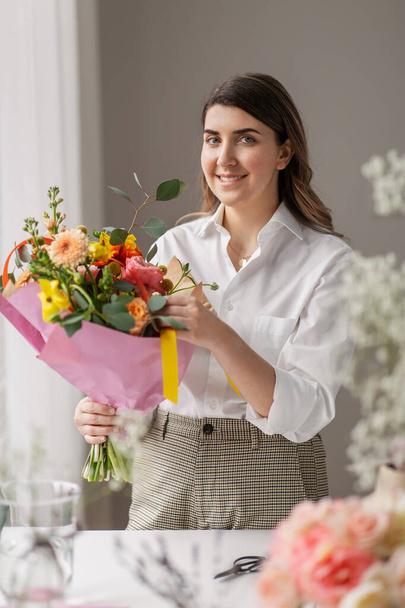 happy woman with bunch of flowers at home - Фото, изображение