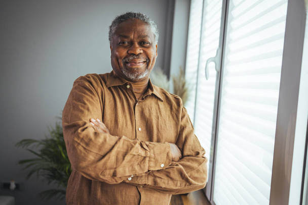 African American Senior Man at home Portrait. Smiling senior man looking at camera. Portrait of black confident man at home. Portrait of a senior man standing against a grey background - Foto, imagen