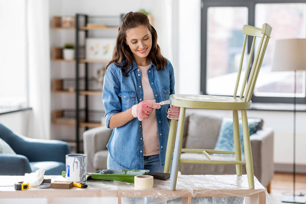 woman painting old chair in grey color at home - Foto, imagen