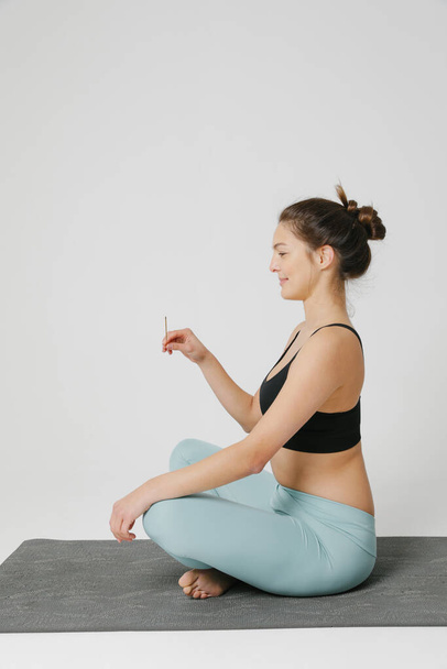 Young woman doing yoga practice isolated on white background. Vertical. - 写真・画像
