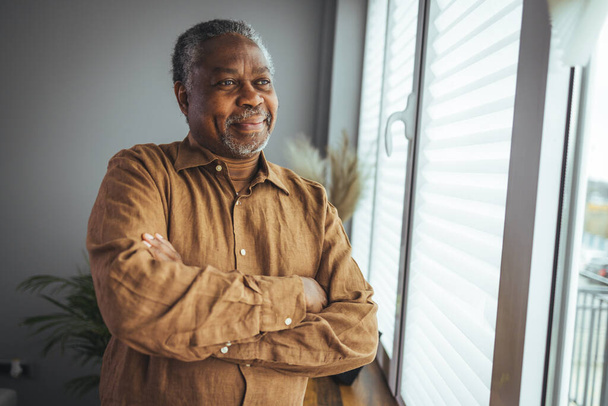 African American Senior Man at home Portrait. Smiling senior man looking at camera. Portrait of black confident man at home. Portrait of a senior man standing against a grey background - Photo, image