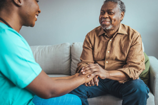 Male patient holding hands with a nurse. Nurse holding hand of senior man in rest home. Doctor helping old patient with Alzheimer's disease. Shot of a caregiver helping a senior man.  - Photo, Image